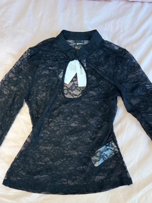 Svart keyhole spetsblus  - Säljer en svart långärmad spetsblus från Gina Tricot i storlek XS. Toppen har ett hål men det går lätt att sy ihop (det fanns där när jag köpte den) säljer då jag inte kan lämna tillbaka