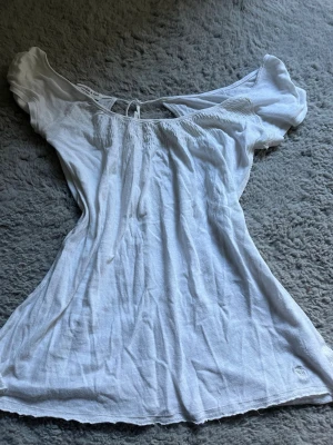 Vit offshoulder topp Abercrombie - Säljer en vit offshoulder topp från Abercrombie & Fitch i storlek M. Toppen har korta ärmar, smockad överdel och knyt i ryggen. Perfekt till sommaren och enkel att styla med jeans eller kjol.