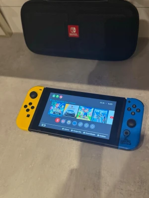 Nintendo switch - Nintendo Switch spelkonsol med en blå och en gul Joy-Con-kontroll. Medföljer gör även ett svart fodral med Nintendo Switch-logga. Perfekt för gaming både hemma och iväg. Pris kan diskuteras