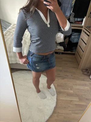 Randig trekvartstopp med vit krage - Snygg trekvartstopp med marinblå och grå ränder, vit krage och vita muddar vid ärmsluten 💕Den är från Nelly i storlek M. Aldrig använd, endast testad och etiketterna är bortklippta. Kontakta gärna för mer info 🥰
