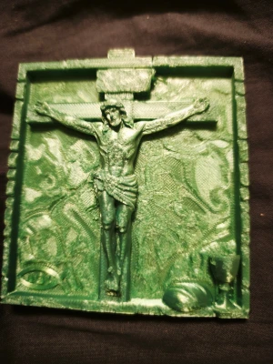 Grön 3D-printad Jesus på korset - En rektangulär grön 3D-printad tavla med Jesus på korset i relief. Tavlan har detaljer som kalk och bröd i hörnet och ett mönstrat bakgrundsmotiv. Perfekt för dig som gillar unika religiösa dekorationer.