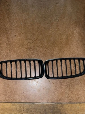 Svarta njurgrillar till BMW - Säljer ett par svarta njurgrillar i plast till BMW. Klassisk design med vertikala ribbor, passar till bilens front. Perfekt för dig som vill ge bilen ett sportigare utseende.