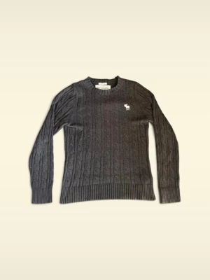 Mörkgrå kabelstickad abercombie & fitch - Mörkgrå kabelstickad tröja med rund halsringning och långa ärmar. Tröjan har ribbade muddar vid ärmslut och nederkant samt en vit broderad logga på bröstet. Perfekt för dig som gillar klassisk och stilren look.