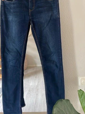 Levisjeans  512 Slim Taper Mörkblå raka jeans - Säljer ett par mörkblå Levis jeans med raka ben och klassisk femficksmodell. Jeansen har kontrastsömmar och är tillverkade i denim med lätt tvättade detaljer. Perfekta för en avslappnad och stilren look.