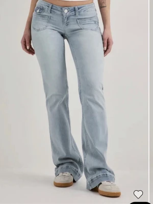 Ljusblå bootcut jeans med låg midja - Säljer ett par ljusblå bootcut jeans med låg midja och klassiska fem fickor. Jeansen har en snygg tvätt och utsvängda ben, perfekta för en avslappnad och trendig look. Tillverkade i denim med stretch för extra komfort.