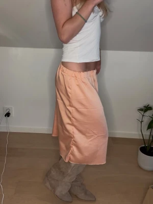Korall midikjol  - Midikjol i underbar korall färg. Satinkjolen är sydd av mig, så helt unik!! Passar xs-m eftersom det är resår i midjan🌸