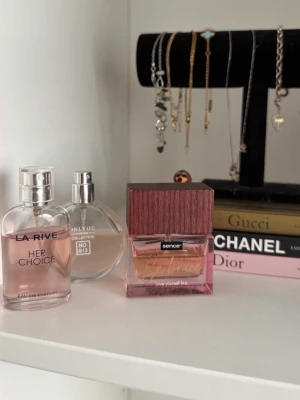 Tre parfymer i rosa och trädetaljer - Säljer tre parfymer: en från La Rive med rosa vätska och silverlock, en rund flaska från Only You Collection No 813 med metallock samt en fyrkantig parfym från Sence med träliknande lock och rosa-orange vätska. Snygga flaskor som piffar upp badrumshyllan. Den första men lukten av rosa blommor, den andra elegnat vanilj, den tredje vanlij, blommor! 20kr för alla tre!!