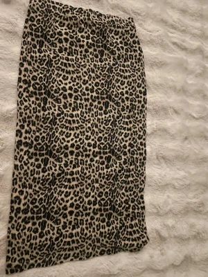 Leopardmönstrad kjol - Snygg kjol med leopardmönster i beige och svart. Kjolen har rak passform och resår i midjan för extra komfort. Perfekt för dig som vill sticka ut med ett trendigt djurmönster. Materialet känns mjukt och följsamt.