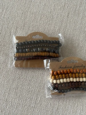 Set med pärlarmband i jordnära färger 2x5 Pack - Säljer två set med pärlarmband i olika jordnära färger som svart, brun, beige och gul. Armbanden är gjorda av trä- och plastpärlor i olika former och storlekar, perfekta för att mixa och matcha till din stil.