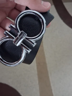 FG bälte - Snyggt svart bälte med bred rem i skinn och en stor, rundad silverspänne framtill. Perfekt för att lyfta vilken outfit som helst med sin stilrena och moderna look. Passar till jeans eller byxor för en trendig touch. Priset är ej fast, kom o förhandla!