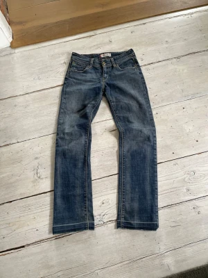 Levi's 570 Straight Fit jeans blå - Ett par klassiska blå Levi's 570 Straight Fit jeans med rak passform. Jeansen har fem fickor, normal midja och slitningar för en cool, avslappnad look. Tillverkade i slitstark denim med kontrastsömmar och knappgylf.