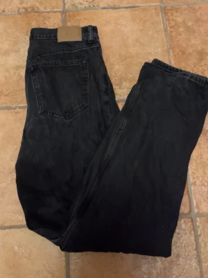 WEEKDAY galaxy loose jeans - Säljer ett par svarta jeans med rak passform och klassisk femficksdesign. Jeansen har hög midja och är tillverkade i ett kraftigare denimtyg. Perfekta för dig som gillar en tidlös och avslappnad stil.