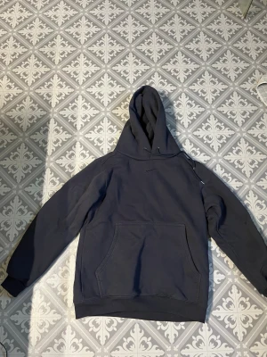 Svart hoodie från Nike med huva - Säljer en svart hoodie från Nike med klassisk huva och dragsnören. Hoodien har en stor magficka framtill och den ikoniska Nike-loggan broderad på bröstet. Perfekt för en avslappnad och sportig stil.