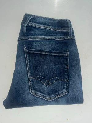 Replay Anbass jeans  - Mörkblåa Replay Anbass jeans med snygg ljus fade med skön och slim passform. Midja 37cm, längd 108cm. - se bild. Längdstorleken saknas, jag skulle bedöma till L34 alternativt långa L32 men utgå efter mått. JAG SKICKAR EJ FLER BILDER NÄR JAG BÄR JEANSEN! för bättre inblick i passformen rekommenderar jag att googla på modellnamnet. För storleksguide kolla måtten noggrant då jeansen alltid kan vara uppsydda heller krympta och jag ej tar emot returer :) (r23)