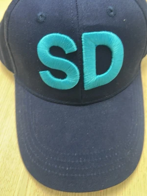 Sd keps - A navy blue baseball cap with large, light blue embroidered 'SD' letters on the front panel. The cap has a curved brim and standard stitched eyelets.