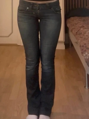 Mörkblå vintage bootcut jeans - Snygga mörkblå bootcut jeans med klassisk femficksdesign och kontrastsömmar. Jeansen har en lätt tvättad look med markerade sömmar och är tillverkade i stretchigt denimtyg för skön passform. Perfekta för dig som gillar en tidlös och trendig stil.