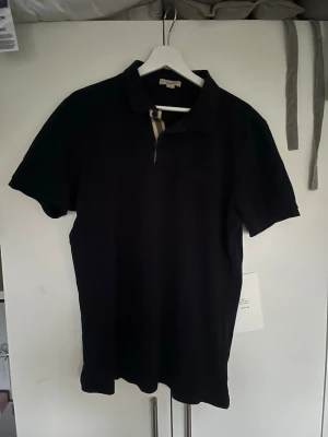Mörkblå pikétröja från Burberry  - Mörkblå piketröja från Burberry. Storlek XL men passar L. Mycket bra skick!