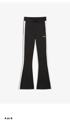 Svarta utsvängda leggings från Puma - Snygga svarta leggings från Puma med vita ränder längs sidorna och utsvängda ben. Tillverkade i ett stretchigt material som sitter skönt och följer kroppen. Perfekta för en sportig och trendig look.