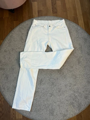 Vita Ralph Lauren jeans - Säljer ett par vita jeans med rak passform och klassisk femficksdesign. På myntfickan finns en broderad RL-detalj i rött. Jeansen har bälteshällor och stängs med knapp och dragkedja. Perfekta för en clean och stilren look.