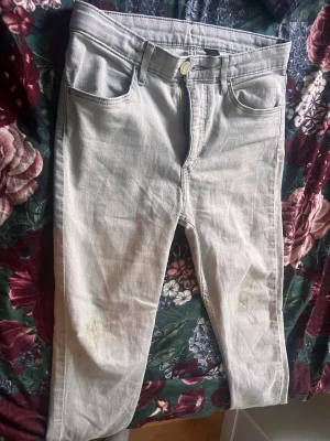 Ljusgrå raka jeans - Säljer ett par ljusgrå jeans med rak passform och klassisk femficksdesign. Jeansen har bälteshällor, knappgylf och är tillverkade i ett mjukt denimtyg. Perfekta för en avslappnad och trendig look.