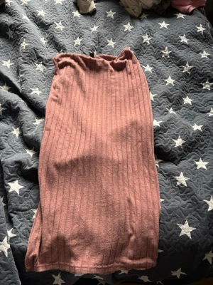 Rosa ribbad långkjol från SHEIN - Säljer en rosa ribbad långkjol från SHEIN i storlek L. Kjolen har en mjuk och stretchig känsla med vertikala ribbade ränder som ger en snygg struktur. Perfekt att styla med en enkel topp eller stickad tröja.