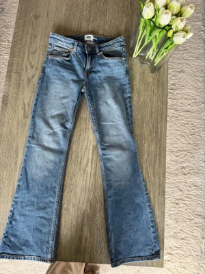 Blå bootcut jeans petite Lager157 - Säljer ett par blå bootcut jeans i klassisk denim  och fem fickor. Jeansen har en snygg tvätt och utsvängda ben som ger en retrovibe. Perfekta för dig som gillar en avslappnad men trendig stil. Aldrig använt dessa, nya. Storlek XS short length dvs petite 