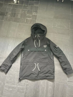 Svart vindjacka från Dope - Snygg svart vindjacka från Dope med stor magficka, dragkedja i sidan och justerbar huva med vita snören. Använd 1 vecka när jag var i fjällen annars legat i garderoben k garaget så ligger bara och tar plats därav säljer jag🤗 nypris 2300:- priset är prutbart🙌🏻