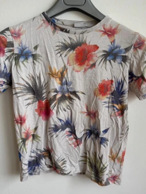 Mönstrad T-shirt Lindex Kids storlek 134/140 (8-10 år) - Färgglad t-shirt från Lindex Kids med ett fint tropiskt mönster  Märke: Lindex Kids  Storlek: EUR 134/140 (passar ca 8-10 år)  Skick: Bra begagnat skick  Material: Mjuk bomullsmix  Kommer från ett rök- och djurfritt hem. Fraktas snabbt! ✨ 