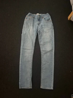 Ljusblå raka jeans - Säljer ett par ljusblå jeans med rak passform och klassisk femficksdesign. Jeansen har normal midja och är tillverkade i denim med en lätt tvättad look. Perfekta för en avslappnad stil och passar till det mesta i garderoben.