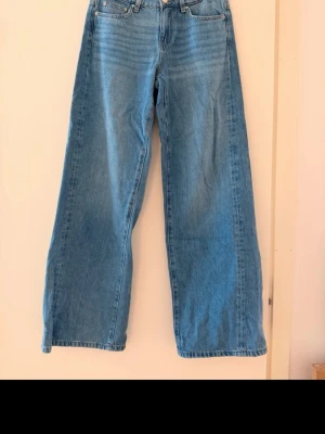 Blåa vida jeans med hög midja - Säljer ett par ljusblå jeans med riktigt breda ben och hög midja. Klassisk femficksmodell med raka sömmar och dragkedja fram. Perfekta för dig som gillar en avslappnad och trendig stil. Materialet är klassisk denim i bomull. Är midwaist
