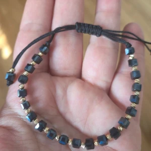 Elegant handgjort armband med guld- & mörka pärlor – Nytt! - Säljer ett supersnyggt, egentillverkat armband i en stilren och lyxig design. Perfekt att bära som det är eller matcha med andra smycken! Design: Facetterade, mörka kubpärlor varvat med glänsande guldfärgade pärlor. Storlek: Justerbar storlek med smidig dragsnodd (passar de flesta handleder).  Skick: 100% helt nytt och oanvänt.Perfekt som present till dig själv eller någon du tycker om! 🌸  Kan skickas med frimärke för 15 kr eller spårbart, säg till innan köp! Samfraktar gärna.