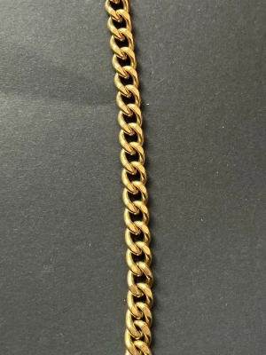 Chunky guldfärgat kedjearmband - Snyggt chunky armband i guldfärgad metall med breda, platta länkar. Kedjan har en klassisk design och stängs med ett karbinlås. Perfekt för dig som gillar statement-smycken och vill addera lite edge till din stil.