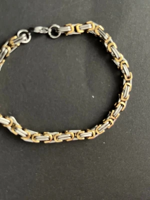 Kedjearmband i guld och silverfärg - Snyggt armband med kedjelänkar i både guld- och silverfärg. Länkarna har en rektangulär form och armbandet har ett klassiskt lås. Perfekt accessoar för att lyfta din stil med en modern touch.
