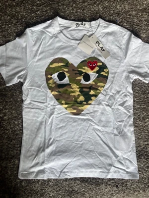 CDG Tshirt Camo Heart - Aldrig använd ✔️, Storlek XL men passar som M-L ✔️, Kommer med tags 🏷, skickas inom 1 dag 🚀, kontakta gärna för mer info ☺️