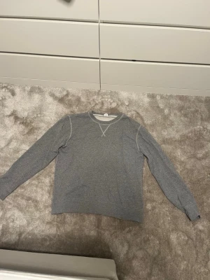 Grå sweatshirt från Arket  - En basic grå sweatshirt från Arket med kontrasterande vita sömmar och klassisk rund halsringning. Storlek M