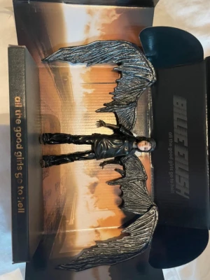 Billie Eilish figur med svarta vingar - Samlarfigur inspirerad av Billie Eilishs musikvideo 'all the good girls go to hell'. Figuren är ca 15 cm hög, klädd i svarta kläder och har stora svarta vingar. Kommer i en specialdesignad förpackning med motiv från musikvideon.