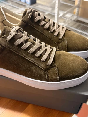 Olivgröna sneakers från Vagabond - Helt Nya  - Snygga olivgröna sneakers från Vagabond i mocka med vita sulor och matchande olivgröna skosnören. Klassisk låg modell som passar perfekt till jeans eller chinos. Skorna har en stilren design och är riktigt bekväma för vardagsbruk. Aldrig använda för pga att jag inte hittat användning för dom. 