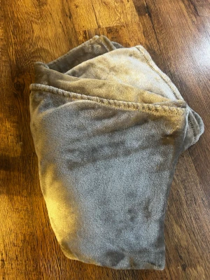 Mjuk grå/beige filt - Superskön och fluffig filt i grå/beige färg från Rusta Home. Perfekt att svepa runt sig för extra värme och stil. Materialet är lent och har en skön känsla. 150x125cm