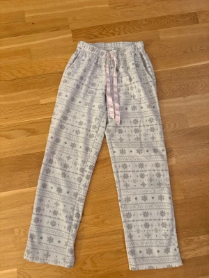 Ljusgrå pyjamasbyxor med mönster - Mysiga ljusgrå pyjamasbyxor med vitt och grått vintermönster och snöflingor. 