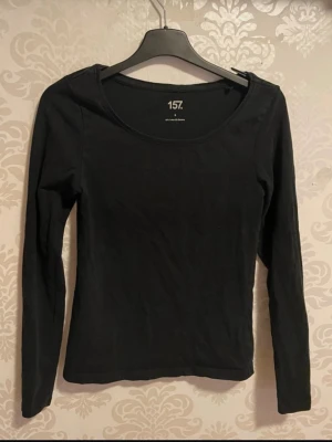Svart långärmad topp - En enkel svart långärmad topp med rund halsringning. Tillverkad i mjuk bomull, perfekt att matcha med jeans eller kjol. Snygg och stilren bas i garderoben.