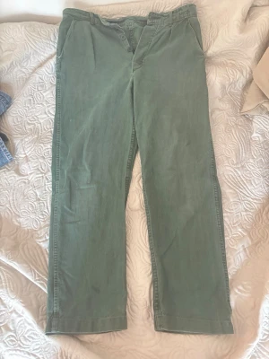 LIMITED Gröna byxor  - Säljer ett par gröna byxor med rak passform och klassisk look. Byxorna har framfickor och en bakficka, samt bälteshällor i midjan. Materialet ser ut att vara bomull eller bomullsblandning, vilket ger en mjuk känsla och avslappnad stil.