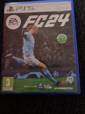 EA Sports FC24 till PS5 - Säljer spelet EA Sports FC24 till PlayStation 5. Omslaget visar en fotbollsspelare i ljusblå matchställ och spelet har PEGI 3-märkning. Perfekt för dig som gillar fotbollsspel och vill spela med de största ligorna och lagen.