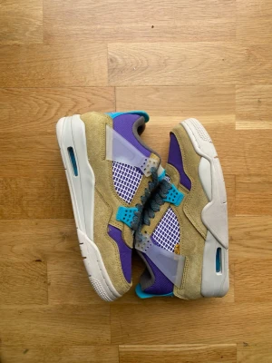 Sneakers i beige och lila mesh och mocka - Unika sneakers med beige mocka, lila meshpaneler och detaljer i turkos och grått. Skorna har vit sula med blå inslag och coola plastdetaljer vid snörningen. Perfekt för dig som vill sticka ut med färg och stil. Kombinationen av material ger en modern och sportig vibe.