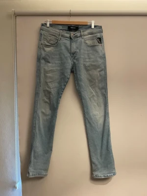 REPLAY hyperflex - Säljer ett par ljusblå jeans med rak passform och klassisk femficksdesign. Jeansen har en något tvättad look och är tillverkade i denim. Perfekta för en avslappnad och trendig stil.