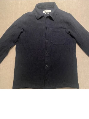 Mörkblå overshirt med bröstficka - Stilren mörkblå overshirt. Funkar som både skjorta och overshirt. Säljer då den är lite tajt