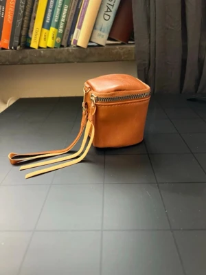 Brun mini väska / smyckesförvaring – vintage style 🤎 - Söt liten brun förvaringsväska i vintage stil 🤎 Perfekt för smycken, små accessoarer, nycklar, hörlurar eller andra småsaker.  • Dragkedja • Praktisk handledsrem • Kompakt storlek, ca 9 × 9 cm • Lätt att ta med i handväskan eller på resan • Ny  Kolla gärna mina andra annonser – köp flera saker tillsammans och spara på frakten 🛍️