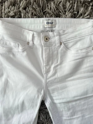 Vita bootcut jeans från ONLY - Snygga vita bootcut jeans från ONLY med klassisk femficksmodell och normalhög midja. Jeansen har en lätt utsvängd passform nedtill och är tillverkade i ett mjukt denimtyg som sitter bekvämt. Aldrig använda!!💕