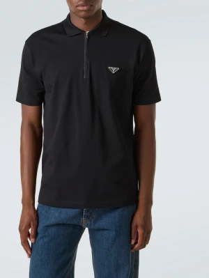 Svart polotopp med dragkedja från Prada - Snygg svart polotopp från Prada med kort ärm och dragkedja framtill. Toppen har en klassisk krage och Pradas ikoniska logga på bröstet. Perfekt till jeans eller chinos för en clean och stilren look.