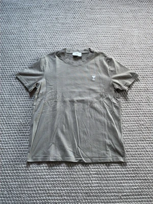 Ami Paris Tshirt - Säljer en stilren Ami Paris tshirt som är lite khaki färgad altså grön beige ish | Storlek S-M passar nog M bäst | Fraktas inom 1 dag