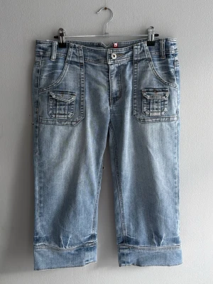 Ljusblå denimshorts med fickor - Snygga ljusblå denimshorts med stora fickor fram och bak, knapp- och dragkedjestängning samt breda benslut. Perfekta för en avslappnad stil och passar till det mesta. Klassisk jeanslook med coola detaljer. 